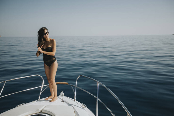 Bella giovane donna in costume da bagno in piedi sul fronte yacht
 - Foto, immagini
