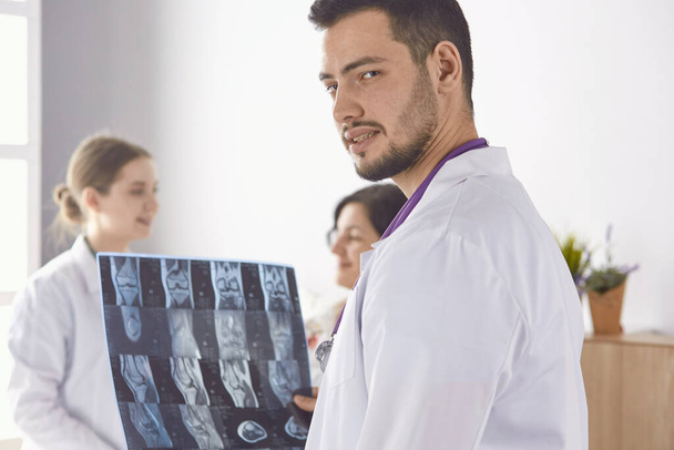 Doctor viendo fotografía de rayos X de una anciana
 - Foto, imagen