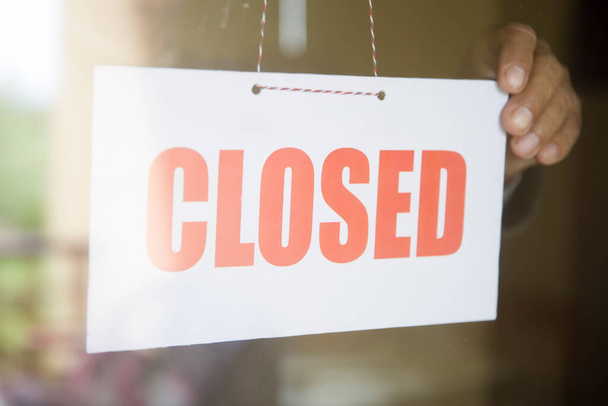 Propietario de tienda de negocios girando cartel cerrado en la puerta de la tienda de vidrio
 - Foto, imagen