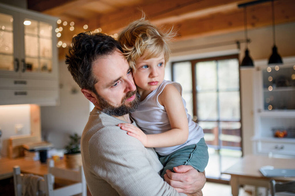 Father with small sick unhappy son indoors at home, comforting him. - Fotoğraf, Görsel