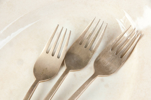 Tre vecchie forchette in bronzo su lastra ovale antica su fondo in cemento. Copia spazio per testo, cibo oggetti di scena fotografia
. - Foto, immagini