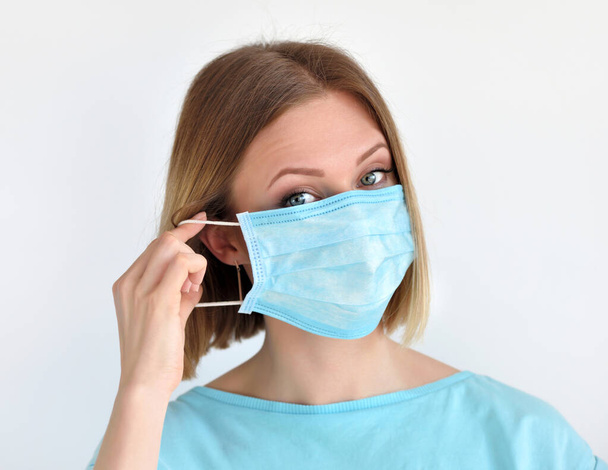 Meisje zet een medisch gezichtsmasker voor bescherming tegen infectie. Gezondheidszorg en medisch concept. - Foto, afbeelding