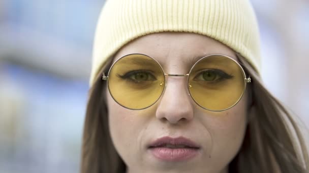 4k. Молода серйозна дівчина в жовтій шапці і окулярах стоїть в районі міста. Крупним планом портрет
 - Кадри, відео