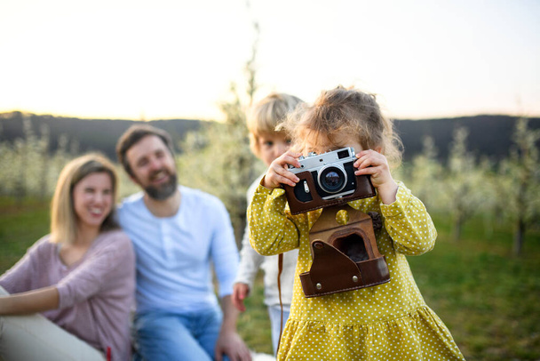 Family with small children sitting outdoors in spring nature, taking photos. - Foto, Imagem