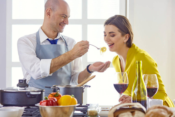 Uśmiechnięta młoda para gotuje jedzenie w kuchni - Zdjęcie, obraz