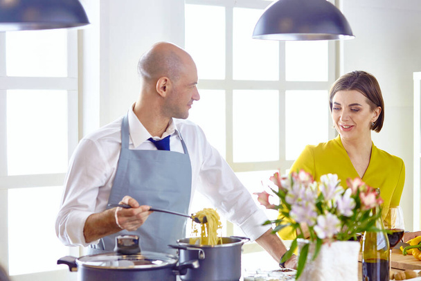 キッチンで若いカップル料理の笑顔 - 写真・画像