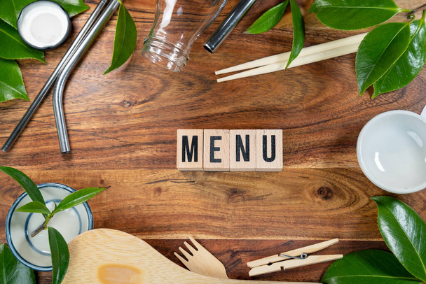 The wooden brick with words " MENU " on wooden background. ECO concept with recycling symbol and leaves. - Photo, Image