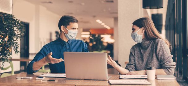 business colleagues in protective masks sitting at the office Desk. - Foto, Imagen