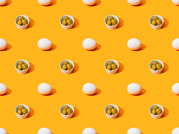 fresh white chicken eggs and olives on orange colorful background, seamless pattern - Photo, Image