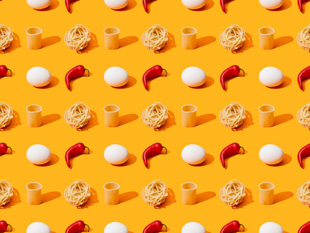 fresh white chicken eggs, pasta and chili peppers on orange colorful background, seamless pattern - Foto, afbeelding