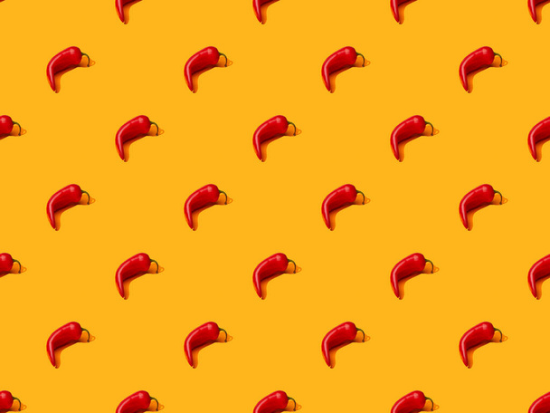 red spicy chili peppers on orange colorful background, seamless pattern - Фото, изображение
