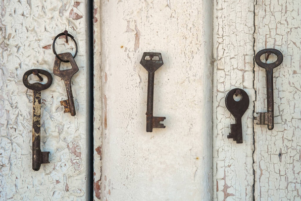 Staré rezavé klíče na dřevěné stěně s polámanou bílou barvou - Fotografie, Obrázek