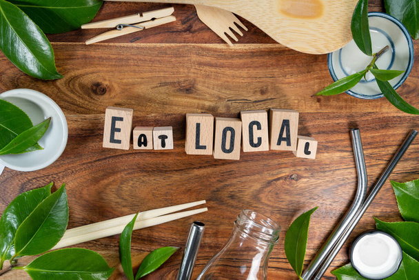 De houten baksteen met de woorden "EAT LOCAL" op houten ondergrond. ECO concept met recycling symbool en bladeren. - Foto, afbeelding