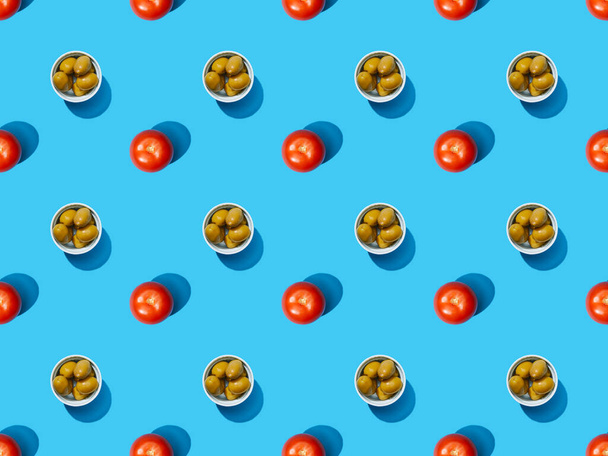 top view of olives in bowls and tomatoes on blue colorful background, seamless pattern - Photo, Image