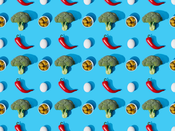 vista superior de brócolis verde fresco, ovos, pimentas e azeitonas em fundo azul, padrão sem costura
 - Foto, Imagem