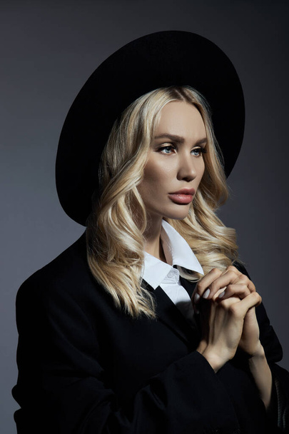 Portrait of a Blonde woman in a big round black hat, hair styling - Photo, Image