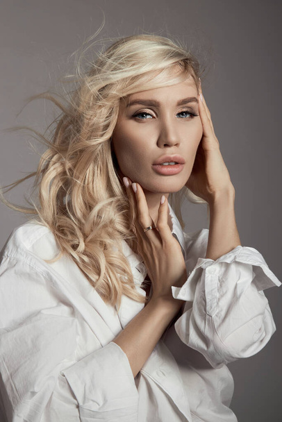 Blonde woman with hair flying in the wind, a close-up portrait of a girl in a white shirt, natural makeup and clean delicate skin - Foto, Imagem