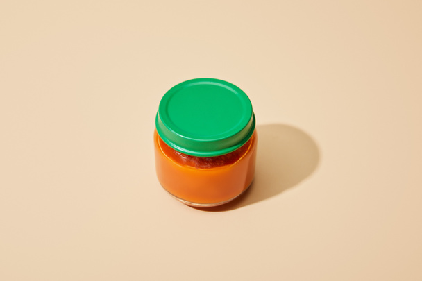 fresh tomato puree in glass jar on beige background - Foto, afbeelding