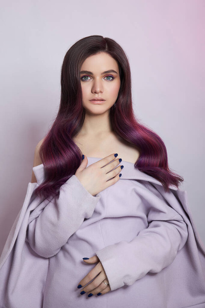 Portrait of a woman with bright colored flying hair, all shades of purple. Shiny Healthy colored Hair coloring, beautiful lips and makeup. Sexy girl with long hair styling - Foto, Imagem