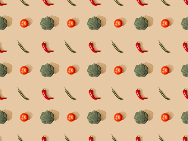 top view of red spicy chili peppers and jalapenos with broccoli and tomatoes on beige background, seamless pattern - Foto, afbeelding