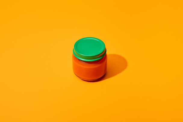 fresh tomato puree in glass jar on orange colorful background - Foto, Bild