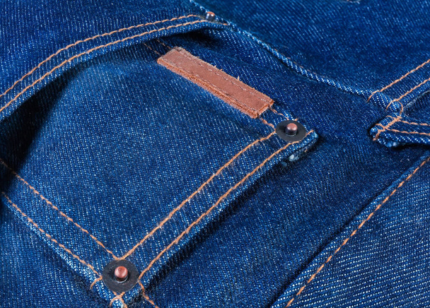 Kieszeń na niebieskich dżinsach z miedzianymi nity i zszyte puste grube etykiety skórzane zbliżenie - Zdjęcie, obraz