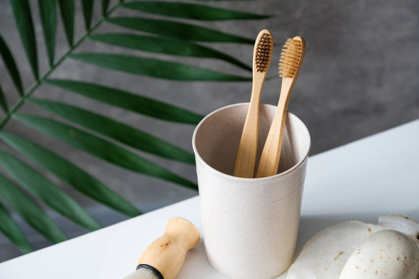 Eco friendly wooden toothbrushes in glass on bathroom table. Natural bamboo toothbrushes for dental care, personal hygiene. Zero waste, plastic free, sustainable lifestyle concept. - Fotoğraf, Görsel