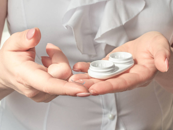 Eyesight and eyecare concept. Woman Hands Holding White Eyelense Container - Photo, image