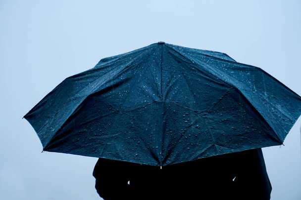 Samotny człowiek stojący w deszczu z parasolem - Zdjęcie, obraz
