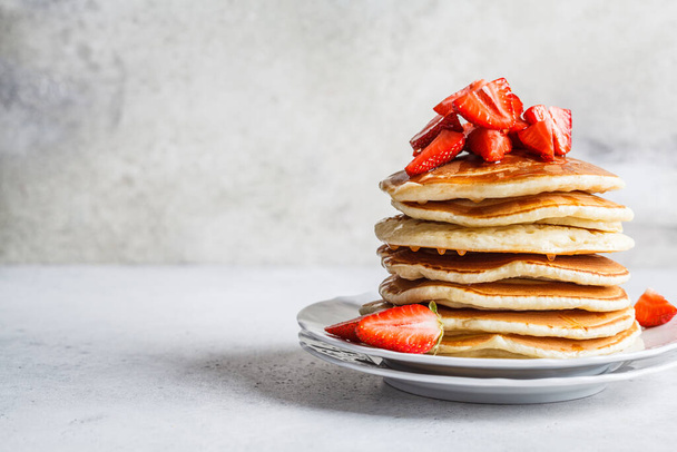 Pancake stack with strawberries and honey on a white plate. - Foto, immagini