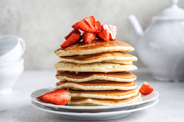 Pancake stack with strawberries and honey on a white plate. - Foto, Bild
