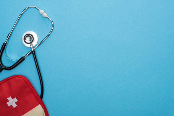 top view of red first aid kit and stethoscope on blue background - Photo, Image