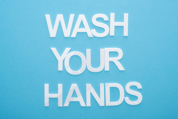 top view of wash your hands lettering on blue background - Foto, afbeelding