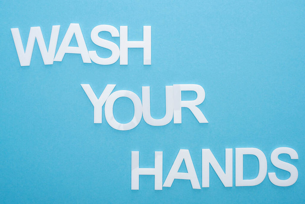 top view of wash your hands lettering on blue background - Фото, изображение