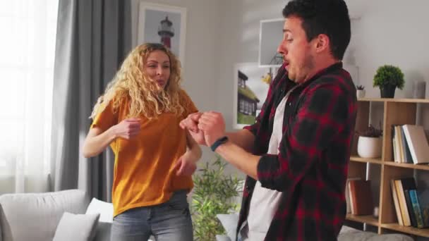 Young cheerful couple funny dancing at home in the living room - Imágenes, Vídeo