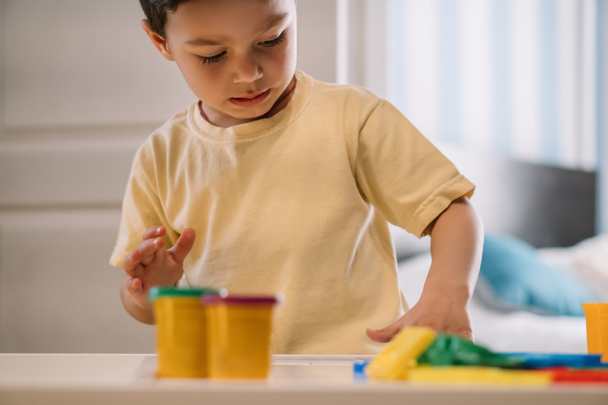 επιλεκτική εστίαση αξιολάτρευτο παιδί παίζει με πολύχρωμα πλαστελίνη  - Φωτογραφία, εικόνα