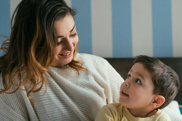 happy mother and adorable son looking at each other in bedroom - Foto, immagini