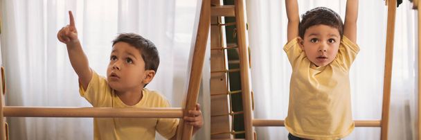 коллаж очаровательного мальчика, указывающего пальцем и висящего на горизонтальной стойке во время занятий в домашнем тренажерном зале, панорамным урожаем
 - Фото, изображение