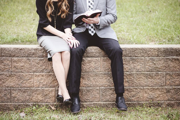 A midsection of a couple sitting on blocks and lovingly reading a book - Foto, imagen