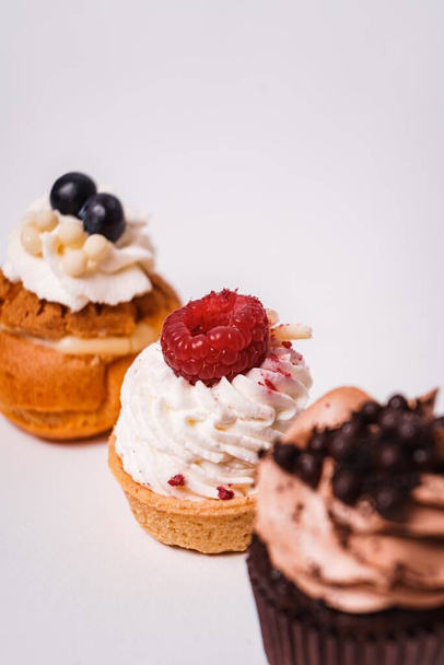 A vertical shot of three delicious and beautifully decorated cupcakes on a white surface - Foto, Imagem