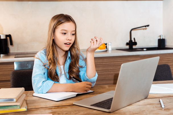 enfoque selectivo de niño sorprendido escribiendo en portátil cerca de la computadora portátil mientras e-learning en casa
 - Foto, Imagen