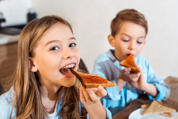 selective focus of cheerful siblings eating toast bread with bread  - Photo, Image