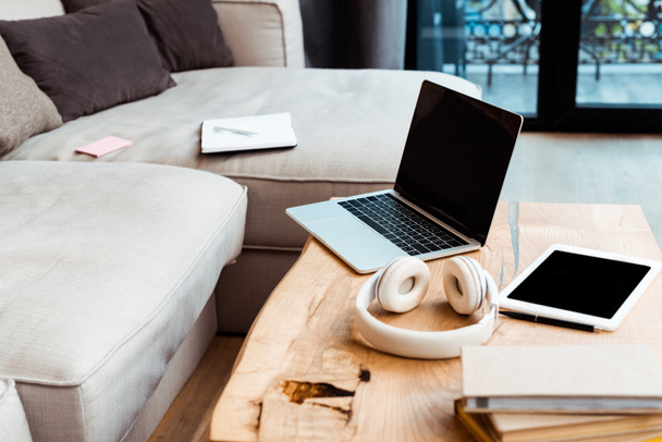 selective focus of gadgets with blank screen near wireless headphones on coffee table - Zdjęcie, obraz
