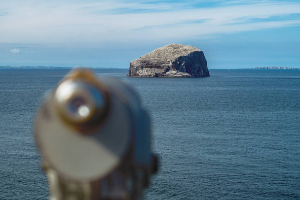 崖の上に灯台があり、手前にはぼかし望遠鏡がある。 - 写真・画像