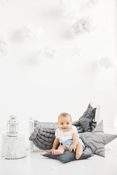 Um portret de um bebê bonito em uma pequena cama em um fundo branco
 - Foto, Imagem