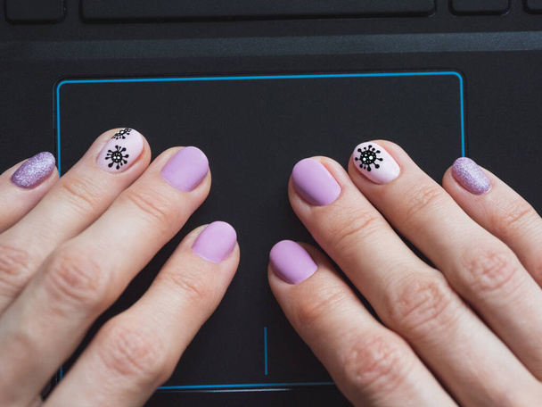 A mão feminina está usando um touchpad em um laptop de perto. Manicure criativo sobre o tema do coronavírus
 - Foto, Imagem