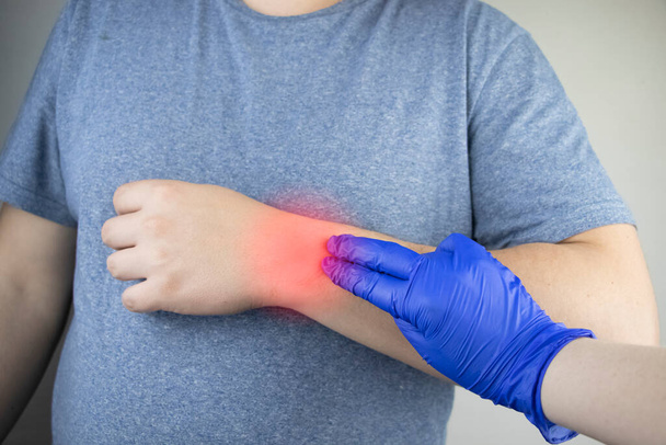 Ο καρπός ενός άντρα πονάει. Τραυματολόγος εξετάζει το χέρι. Πόνος στον καρπό ως ένδειξη συνδρόμου σήραγγας ή διάστρεμμα, εκφύλιση τένοντα, αρθρίτιδα - Φωτογραφία, εικόνα