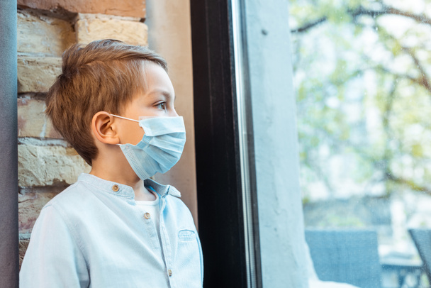 boy in medical mask looking at window  - Fotografie, Obrázek