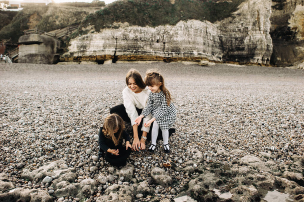 A beautiful young family on the sandy shore of the ocean relaxing and have a fun - Фото, зображення