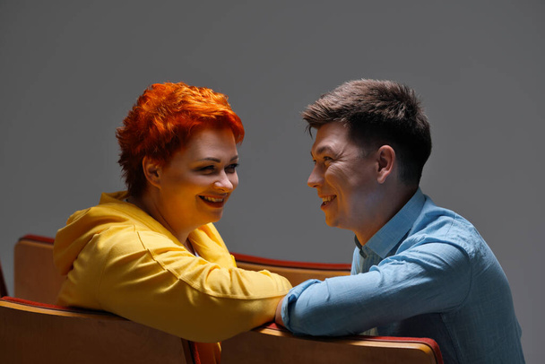 cheerful couple holding hands and sitting on chairs - Foto, afbeelding